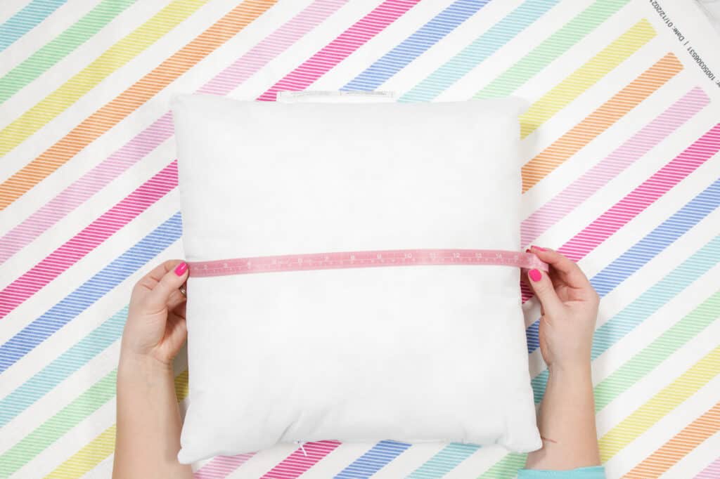 Cut out Fabric for Pillow Case |How to Make an Envelope Pillow Cover With One Piece of Fabric by popular Utah sewing blog, Sweet Red Poppy: image of a woman measuring a square pillow. 