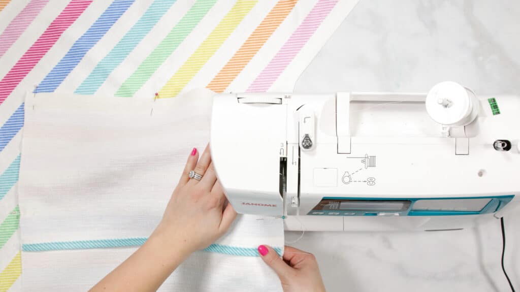 Making an Envelope Pillow Cover Is Easier Than Ever With This Simple Step-by-Step Tutorial and Video Guide! Learn How to Make an Envelope Pillow Cover in Less Than 15 Minutes! |How to Make an Envelope Pillow Cover With One Piece of Fabric by popular Utah sewing blog, Sweet Red Poppy: image of a woman sewing rainbow stripe fabric. 