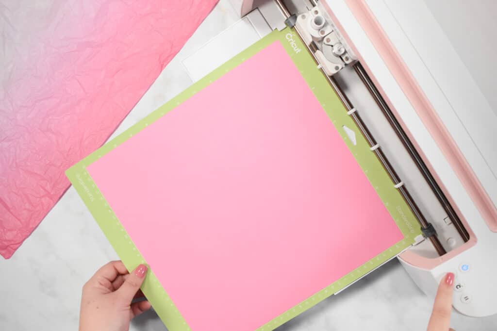 Cricut Shadow Box by popular US craft blog, Sweet Red Poppy: image of  a woman putting pink paper in to a Cricut machine. 