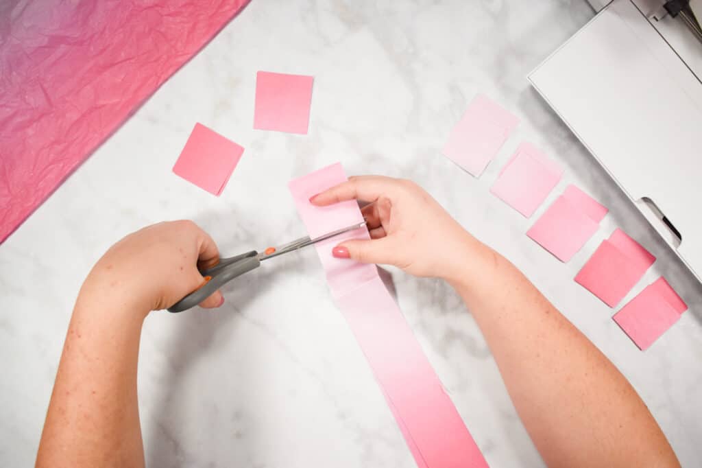 Cricut Shadow Box by popular US craft blog, Sweet Red Poppy: image of  a woman cutting out pink tissue paper squares. 
