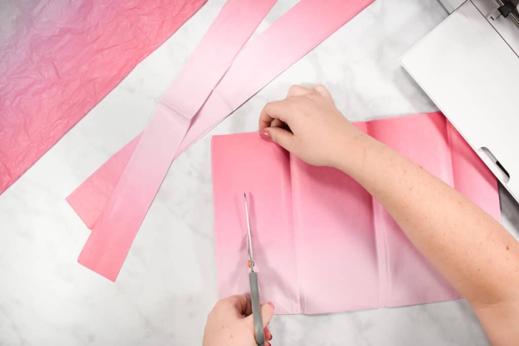 Cricut Shadow Box by popular US craft blog, Sweet Red Poppy: image of  a woman cutting out pink tissue paper squares. 