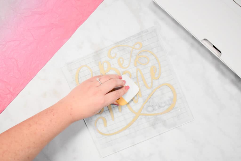 Cricut Shadow Box by popular US craft blog, Sweet Red Poppy: image of  a pressing their scraper tool down onto their vinyl design. 