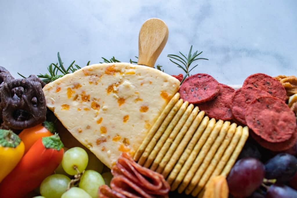 How to Assemble a Charcuterie Board by popular Utah craft blog, Sweet Red Poppy: image of a charcuterie board filled with cheese, nuts, fruit, meat, crackers, dips, vegetables, and yogurt dipped pretzels. 