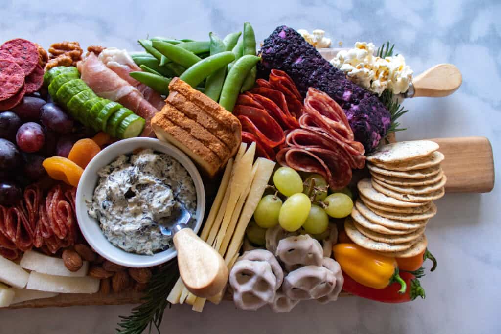 How to Assemble a Charcuterie Board by popular Utah craft blog, Sweet Red Poppy: image of a charcuterie board filled with cheese, nuts, fruit, meat, crackers, dips, vegetables, and yogurt dipped pretzels. 