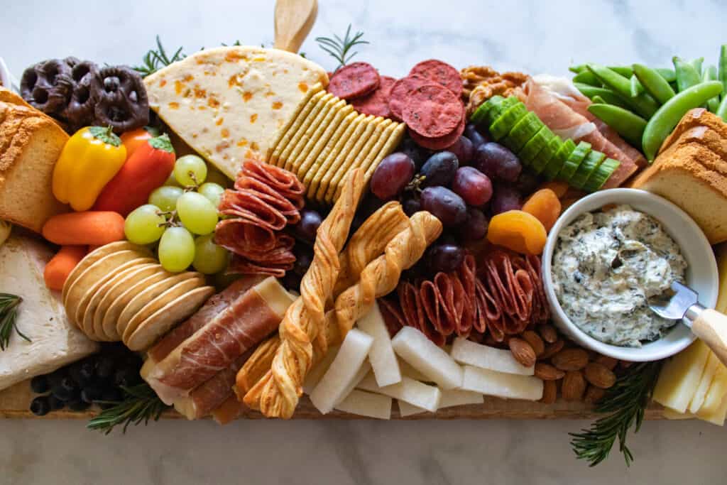 How to Assemble a Charcuterie Board by popular Utah craft blog, Sweet Red Poppy: image of a charcuterie board filled with cheese, nuts, fruit, meat, crackers, dips, vegetables, and yogurt dipped pretzels. 