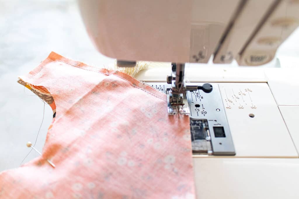 Baby Bib Sewing Pattern by popular US sewing blog, Sweet Red Poppy: image of a fabric bib in a sewing machine. 