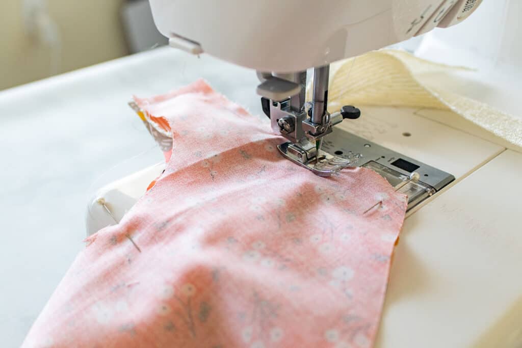 Baby Bib Sewing Pattern by popular US sewing blog, Sweet Red Poppy: image of a fabric bib in a sewing machine. 