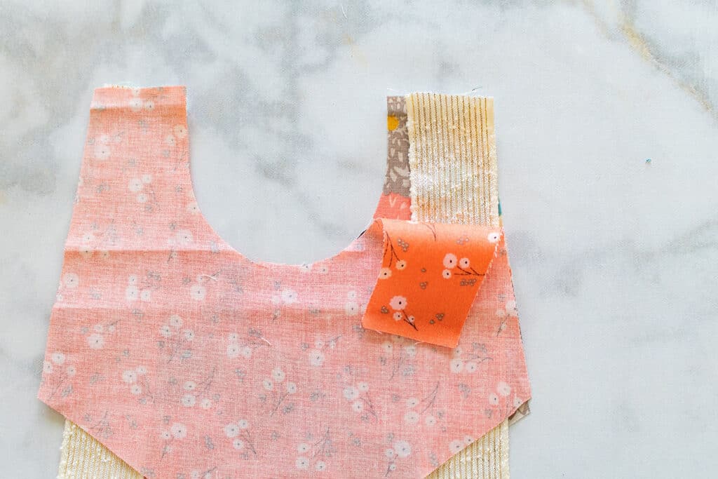 Baby Bib Sewing Pattern by popular US sewing blog, Sweet Red Poppy: image of a ribbon placed in between two piece of bib fabric. 