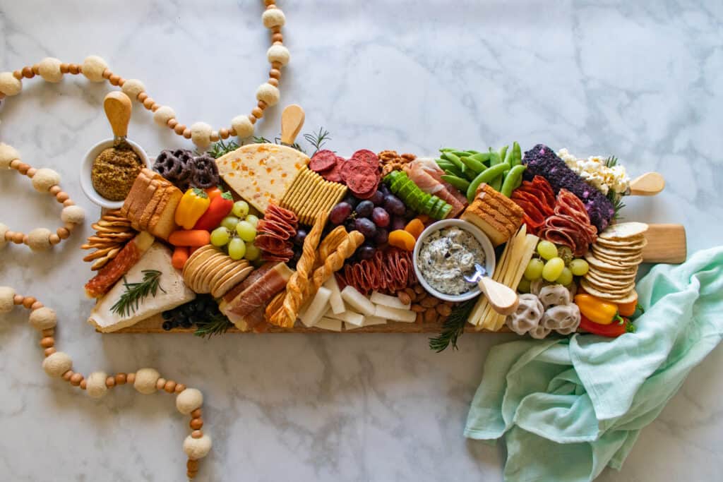 Learn How to Assemble a Charcuterie Board Filled With Cheese, Meats, Crackers, Nuts, Fruits & Vegetables. | How to Assemble a Charcuterie Board by popular Utah craft blog, Sweet Red Poppy: image of a charcuterie board filled with cheese, nuts, fruit, meat, crackers, dips, vegetables, and yogurt dipped pretzels. 