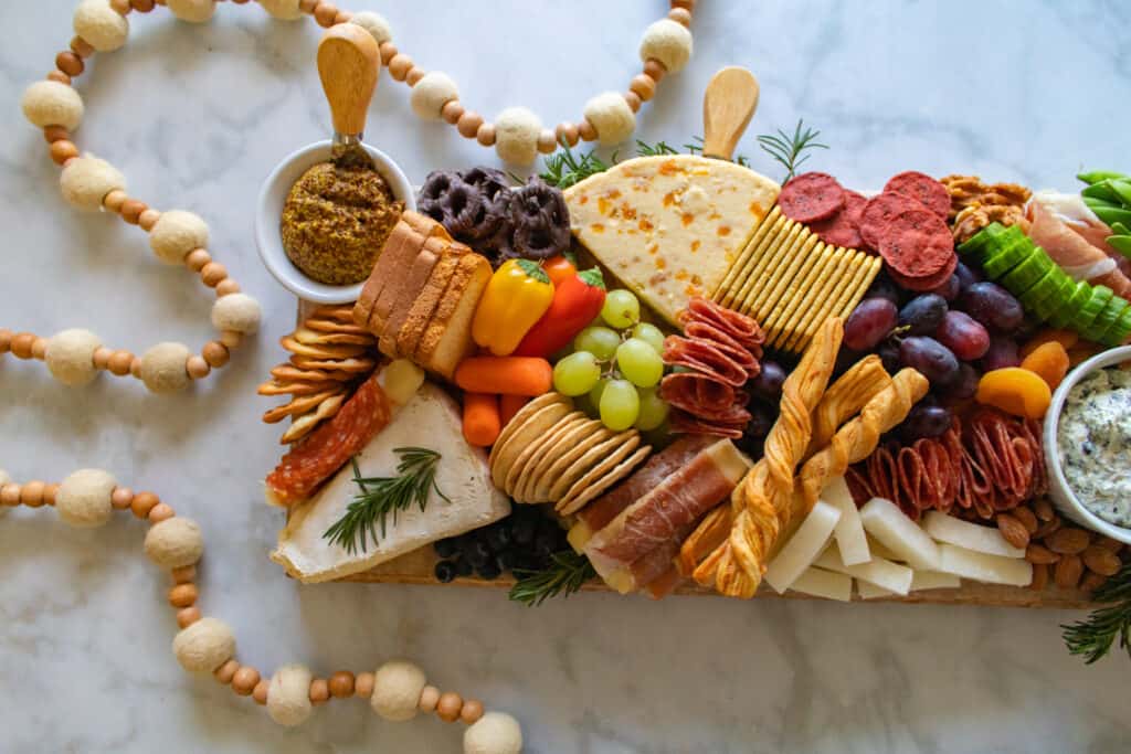 How to Assemble a Charcuterie Board by popular Utah craft blog, Sweet Red Poppy: image of a charcuterie board filled with cheese, nuts, fruit, meat, crackers, dips, vegetables, and yogurt dipped pretzels. 