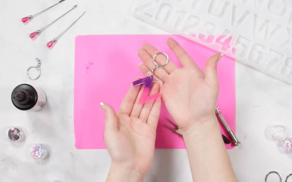 Resin Letter Keychain |Pouring UV Resin |Resin Keychain by popular US craft blog, Sweet Red Poppy: image of a woman pouring resin in to a letter mold. 