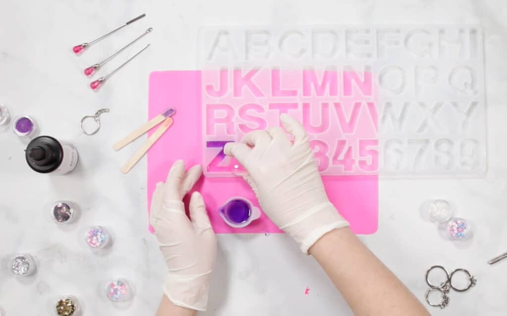 Pouring UV Resin |Resin Keychain by popular US craft blog, Sweet Red Poppy: image of a woman pouring resin in to a letter mold. 
