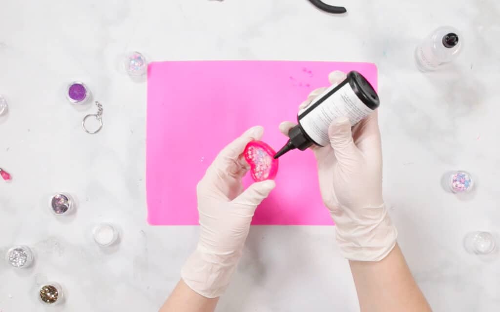 UV Resin by popular US craft blog, Sweet Red Poppy: image of a woman putting shaker oil on her resin shaker. 