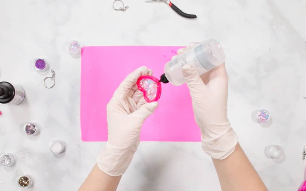 UV Resin by popular US craft blog, Sweet Red Poppy: image of a woman putting shaker oil on her resin shaker. 