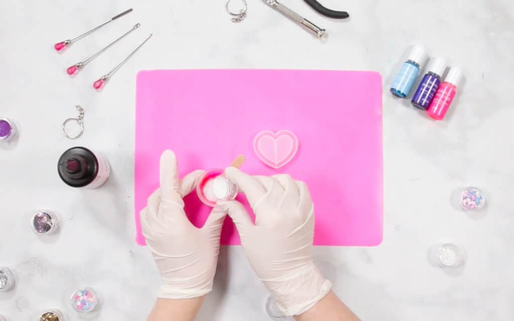 UV Resin by popular US craft blog, Sweet Red Poppy: image of a woman filling resin molds on a resin mat. 