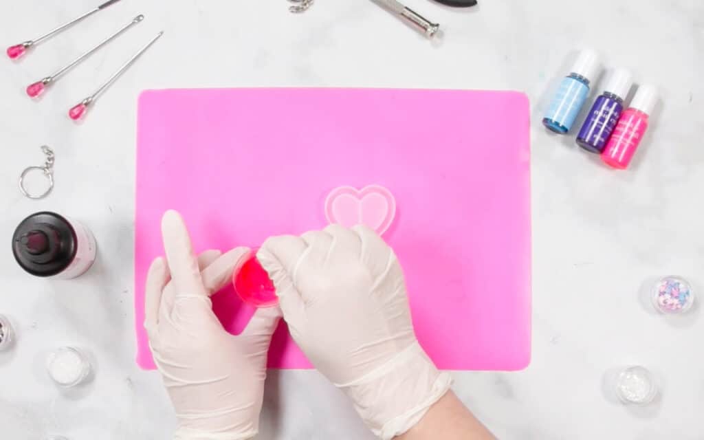 UV Resin by popular US craft blog, Sweet Red Poppy: image of a woman filling resin molds on a resin mat. 