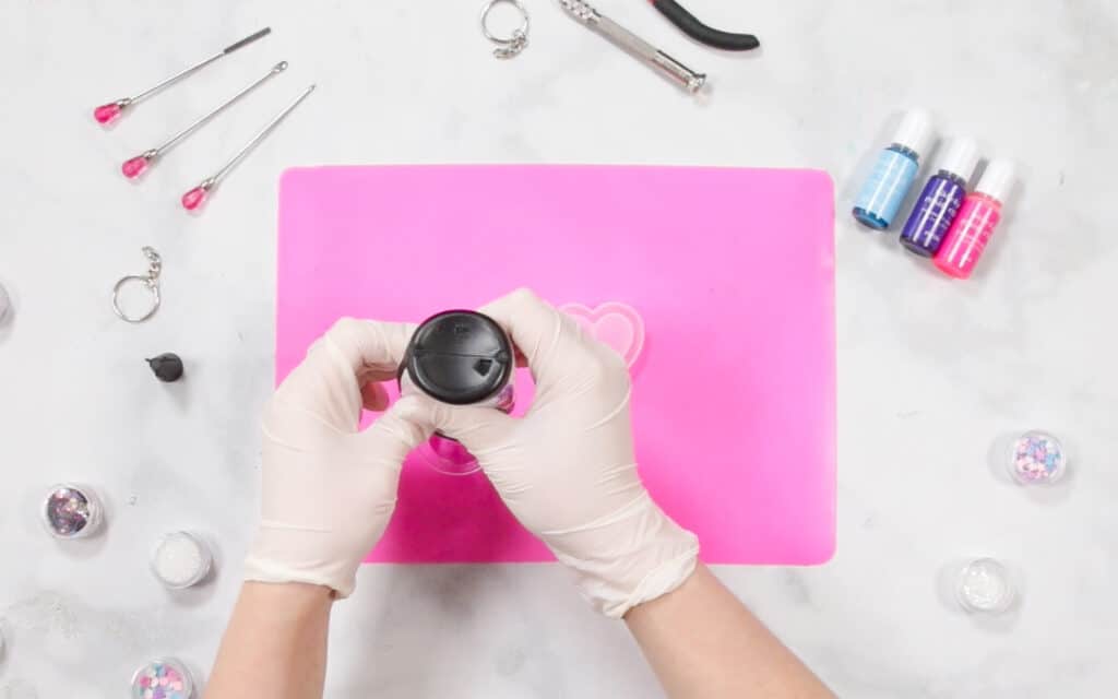 UV Resin by popular US craft blog, Sweet Red Poppy: image of a woman filling resin molds on a resin mat. 