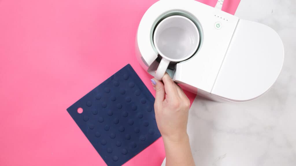 Cricut mug press review featured by top Cricut blogger, Sweet Red Poppy |Cricut Mug Press by popular US craft blog, Sweet Red Poppy: image of a a woman peeling a design backing off of a white ceramic mug. 