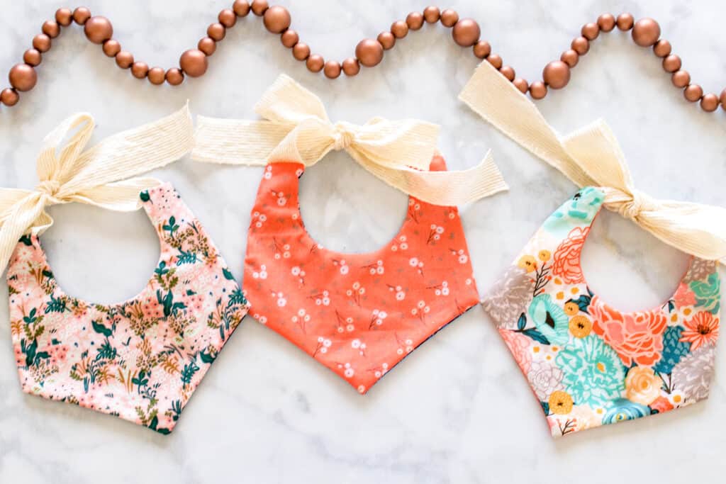 Baby Bib Sewing Pattern by popular US sewing blog, Sweet Red Poppy: image of three cotton fabric baby bibs with yellow ribbon. 