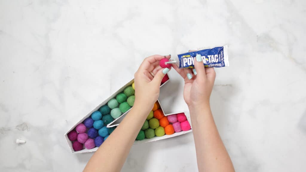 Felt Ball Letters by popular US craft blog, Sweet Red Poppy: image of a white cardboard letter A filled with rainbow felt balls. 