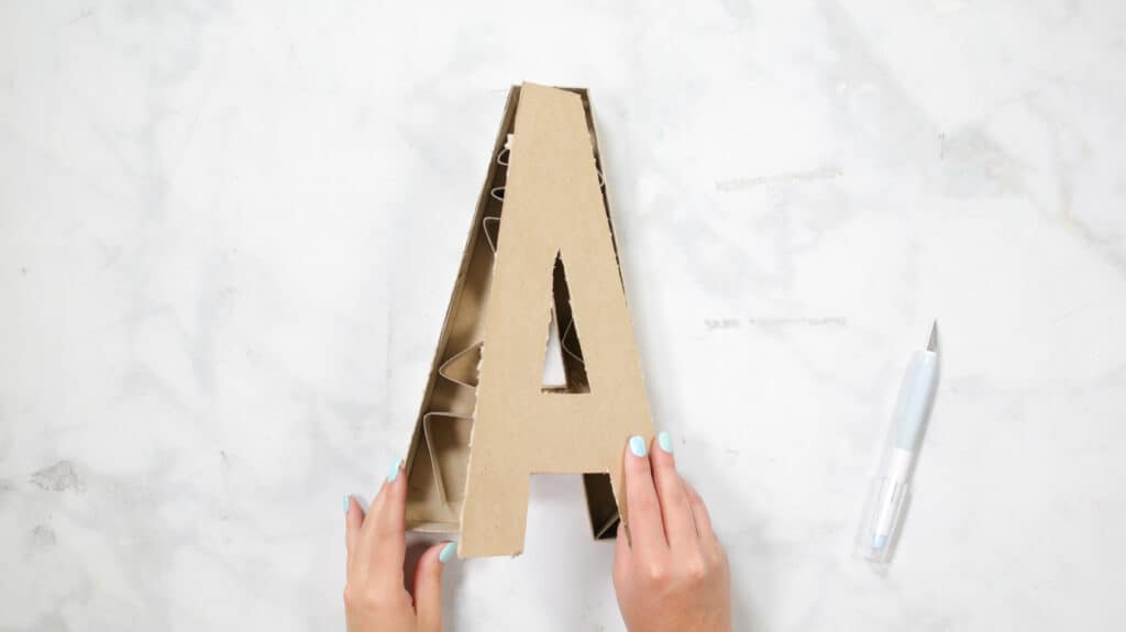 Felt Ball Letters by popular US craft blog, Sweet Red Poppy: image of a woman taking apart a cardboard letter A. 