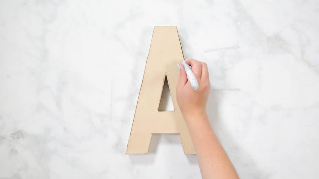 Felt Ball Letters by popular US craft blog, Sweet Red Poppy: image of a woman putting together a cardboard letter A. 