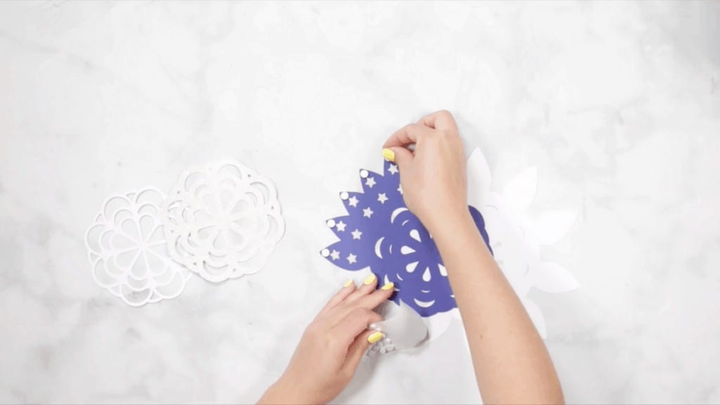 DIY 4th of July Wreath by popular US craft blog, Sweet Red Poppy: image of a woman assembling blue and and white layer wreath pieces. 