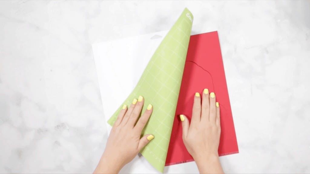 DIY 4th of July Wreath by popular US craft blog, Sweet Red Poppy: image of a woman peeling away a mat from her Cricut paper design. 