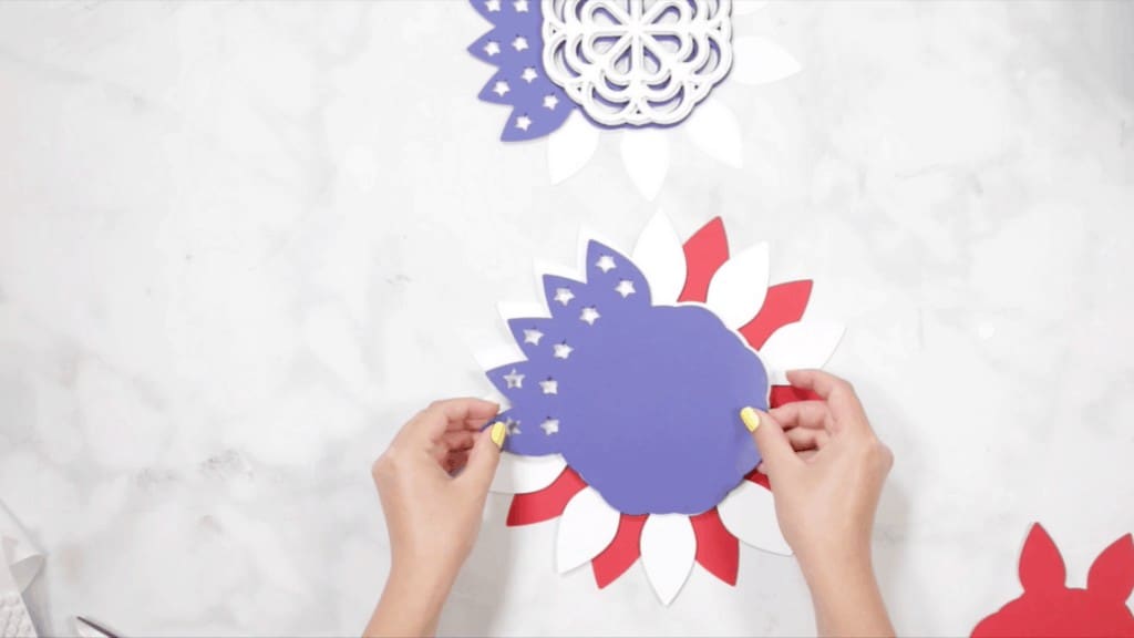 DIY 4th of July Wreath by popular US craft blog, Sweet Red Poppy: image of a woman assembling her blue, white, and red layer wreath pieces. 