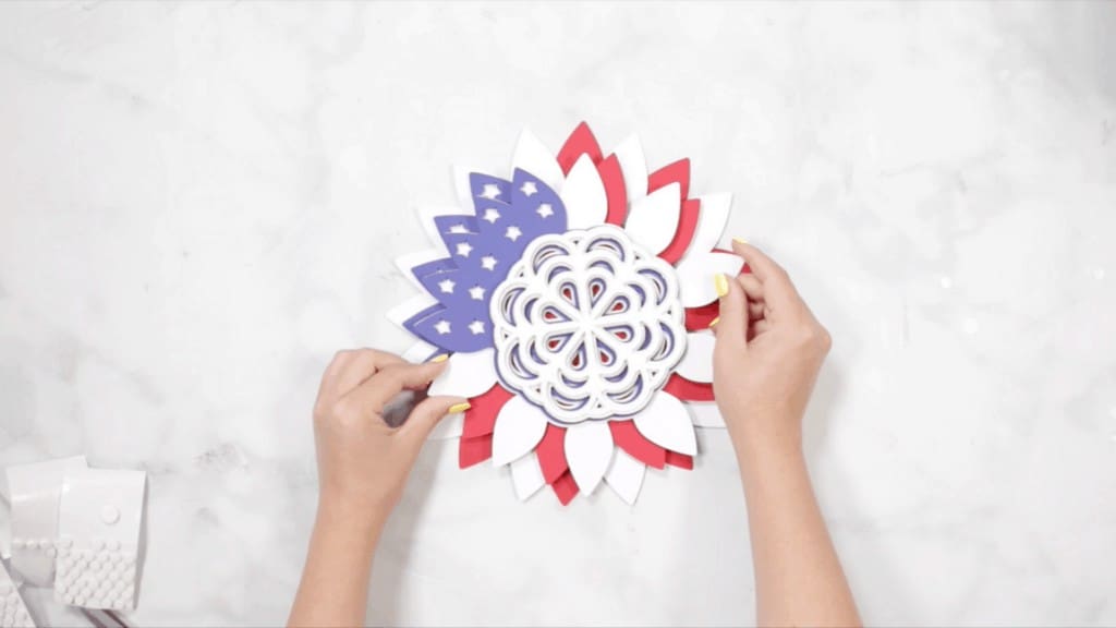 DIY 4th of July Wreath by popular US craft blog, Sweet Red Poppy: image of a woman assembling her blue, white, and red layer wreath pieces. 