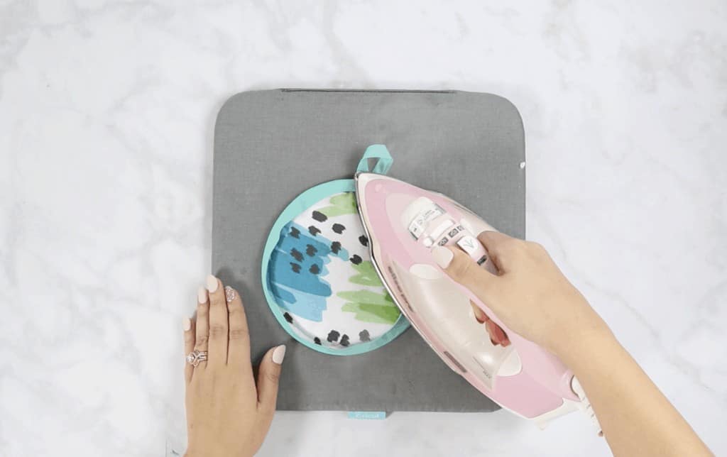 Oven Mitt Sewing Pattern by popular US sewing blog, Sweet Red Poppy: image of a woman ironing a iron kit with a pink iron. 