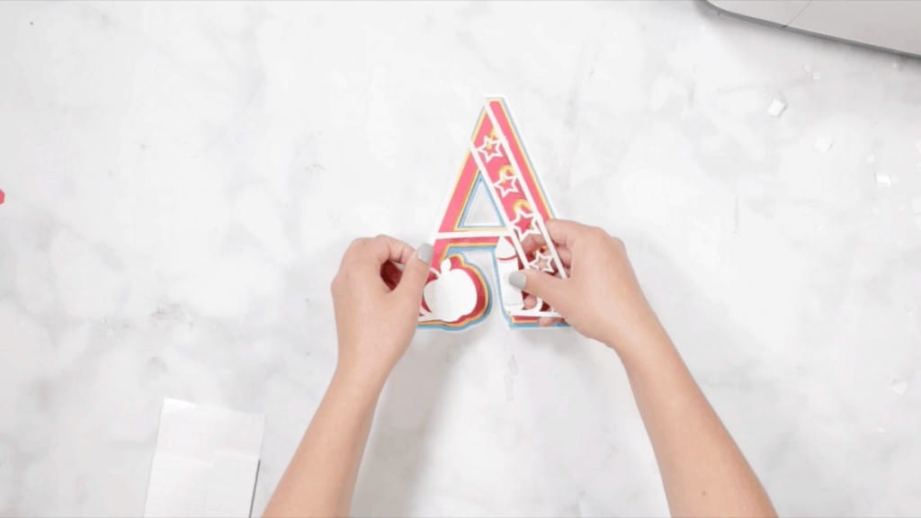 Layered Alphabet by popular US craft blog, Sweet Red Poppy: image of a woman assembling a letter a mandala. 