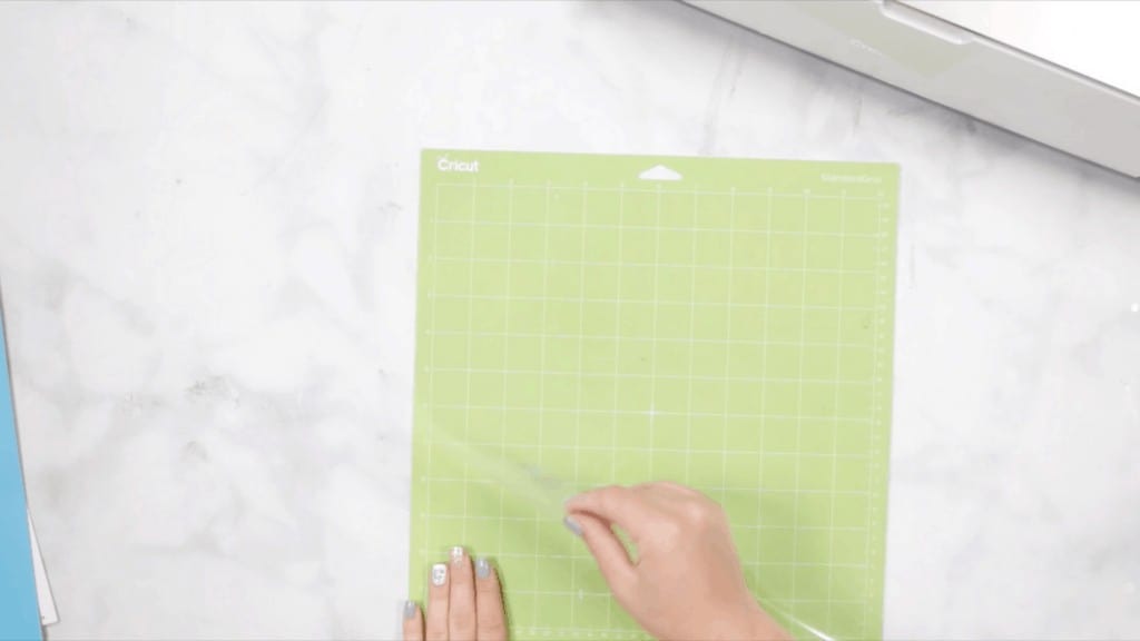 Layered Alphabet by popular US craft blog, Sweet Red Poppy: image of a woman peeling the plastic covering off of a Cricut cutting board. 