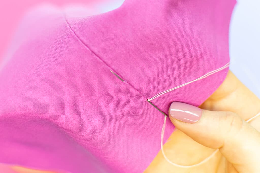 push the needle through the fabric next to the knot