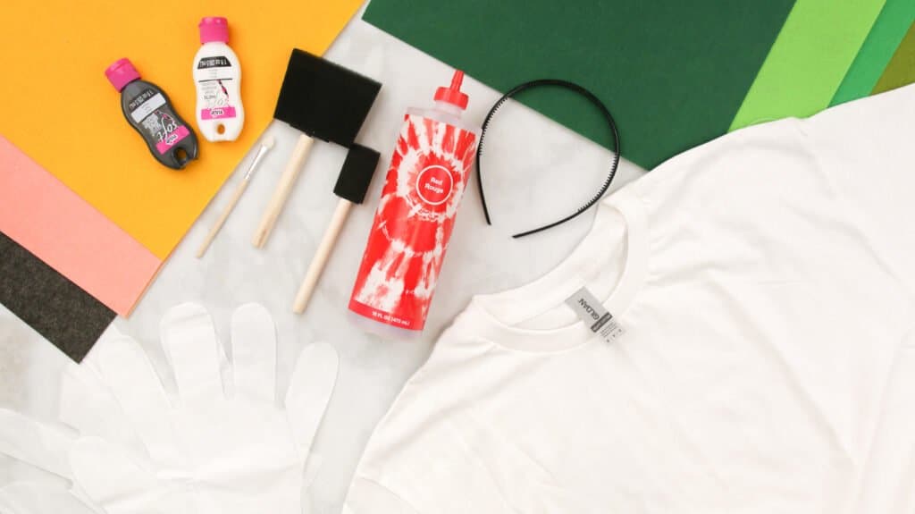 Supplies: Green Felt in different Hues, Yellow Felt, A Tie Dye Bottle, A Headband, Two Foam Paintbrushes, White and Black Tulip Fabric Paint, Gloves, And A White T-Shirt