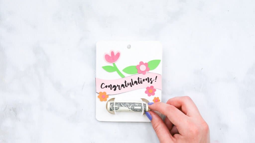 Slipping a roll of money between slots on the congrats money gift card holder
