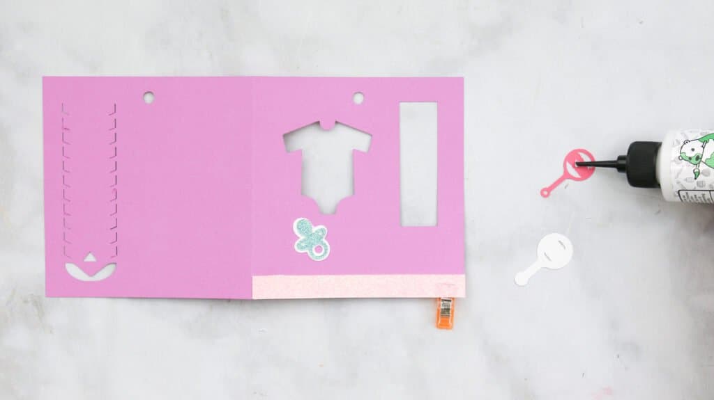 Gluing on baby shower money gift card holder details (pacifier, rattler, and strip) 