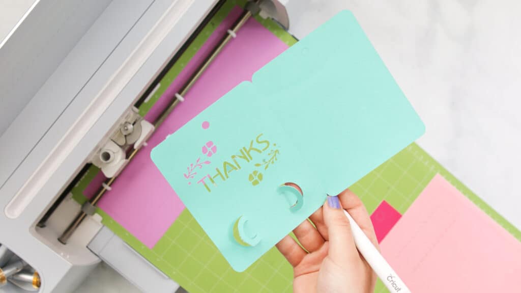 Holding thank you gift card holder above mat and Cricut machine