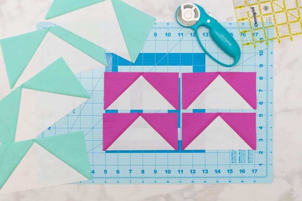 4 squared up pink and white flying geese on a blue cutting mat