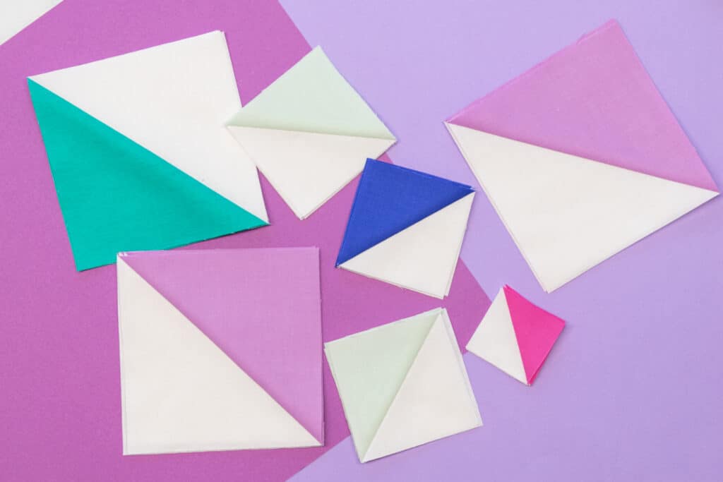 various sizes of half square triangles laid out on a colorful purple backdrop