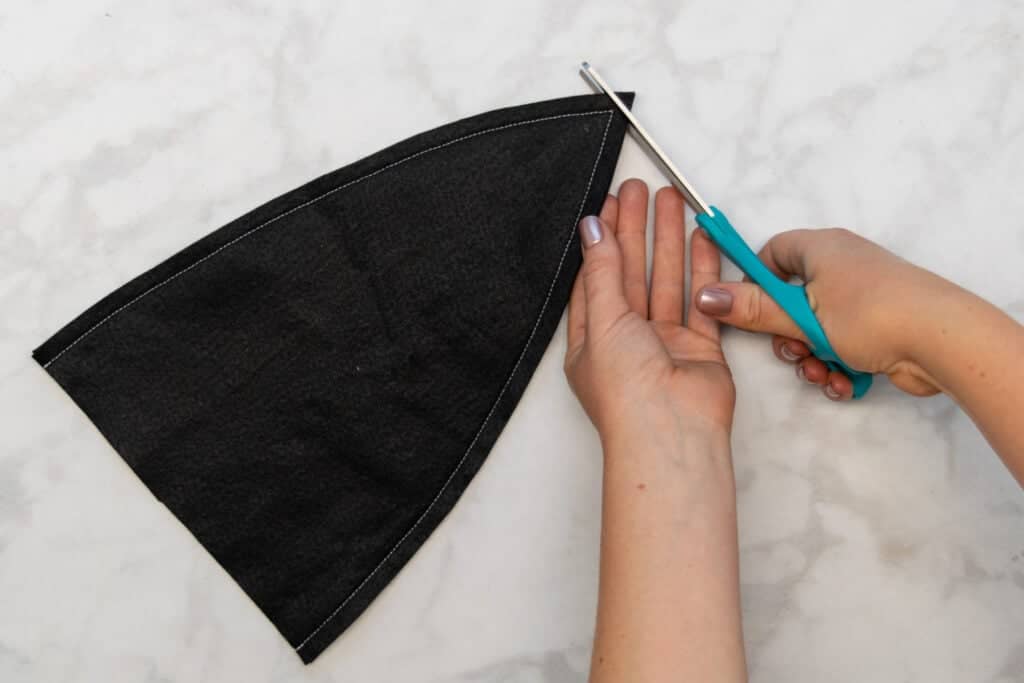 cutting the pointed tip of the witch hat with turquoise scissors