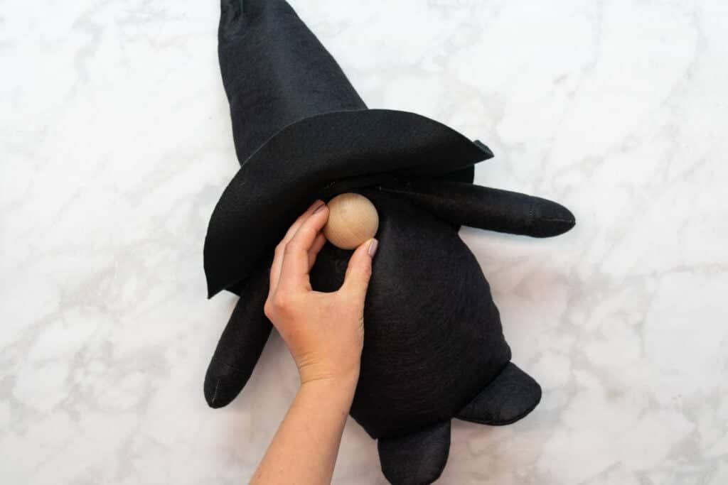 placing a large, round wooden nose on the center of the witch gnome's face