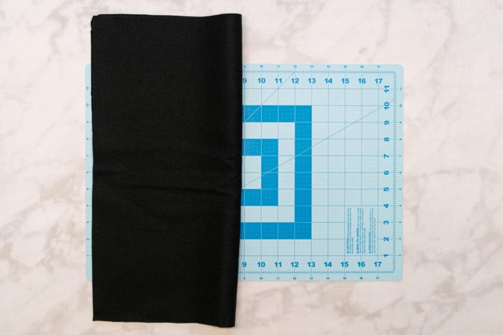 black felt folded in half on a blue cutting mat