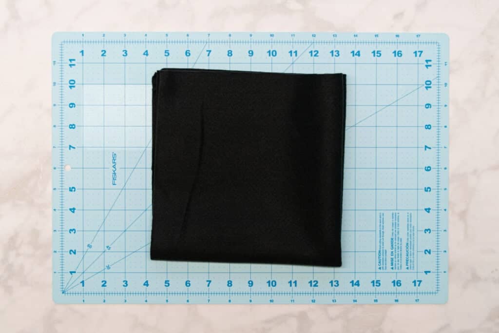 black felt folded in quarters on a blue cutting mat