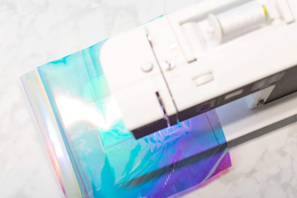 an overhead view of a sheet of holographic vinyl going through a sewing machine