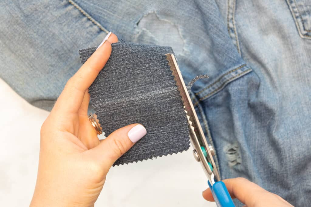 trimming a denim patch with pinking shears
