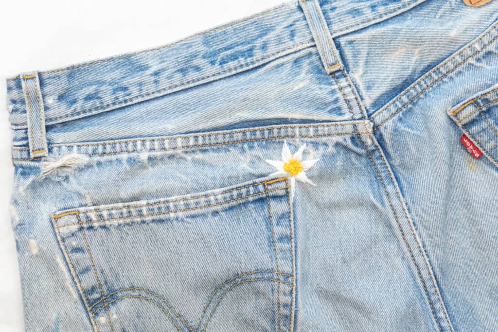 a rip in pants mended with an embroidered daisy