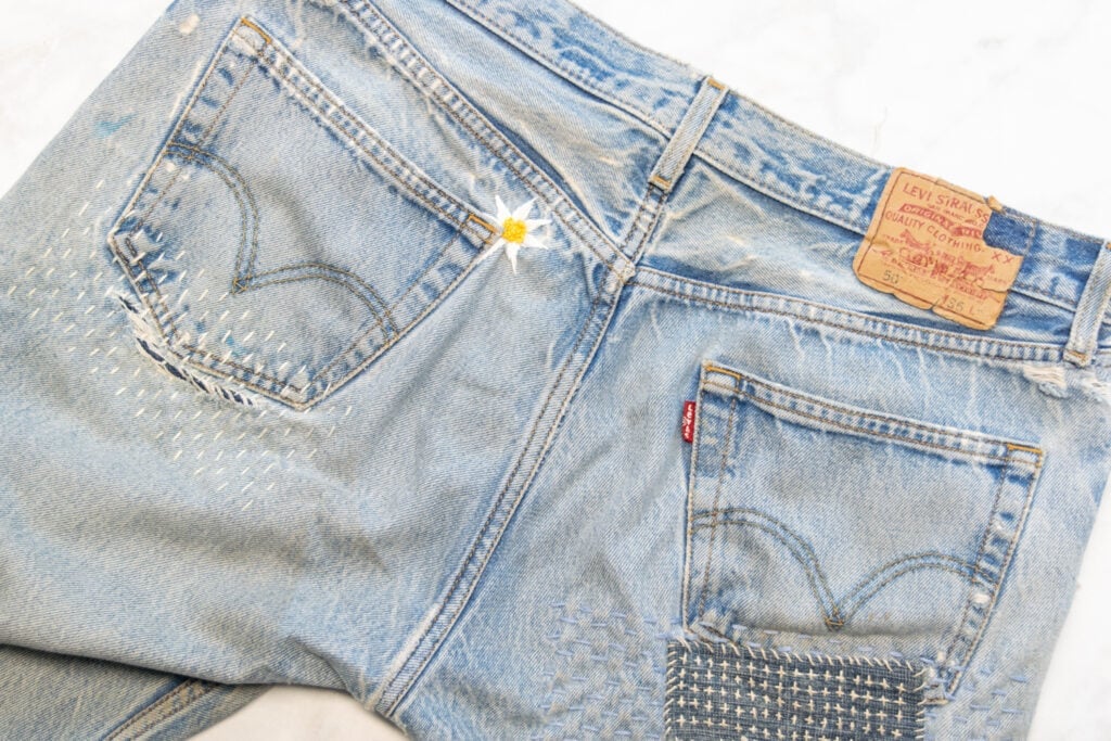 the back of a pair of jeans with several rips mended with embroidery