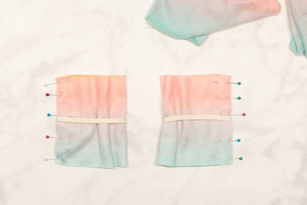 the ombre fleece cuffs are folded in half and the short ends are pinned together with multicolored pins