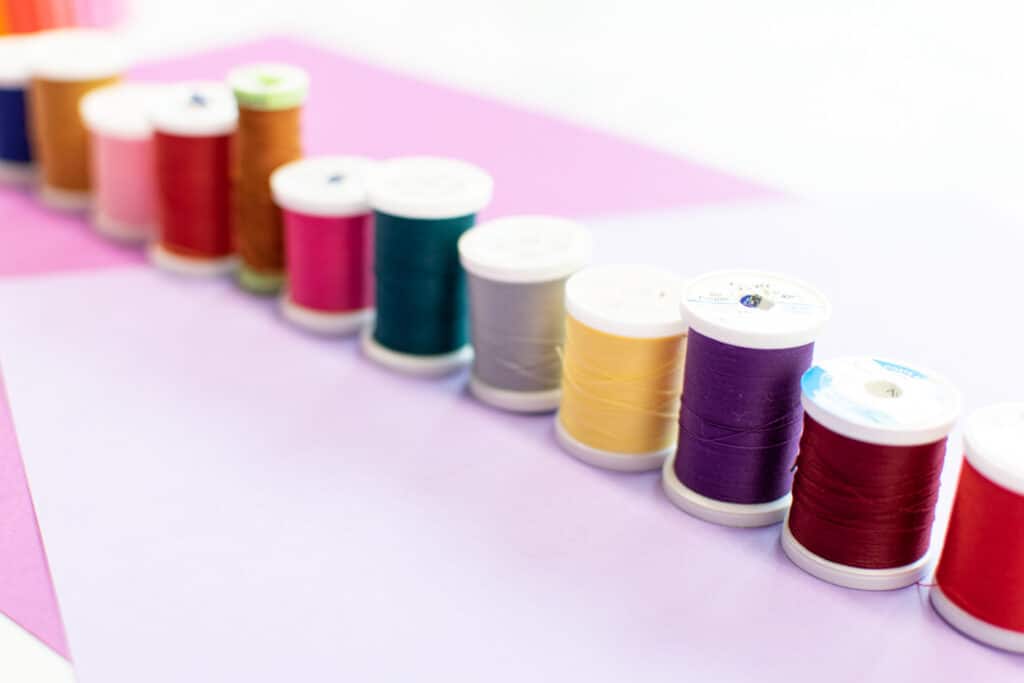 various colors of thread lined up on a colorful background